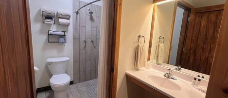 A bathroom with a toilet, shower, and sink.