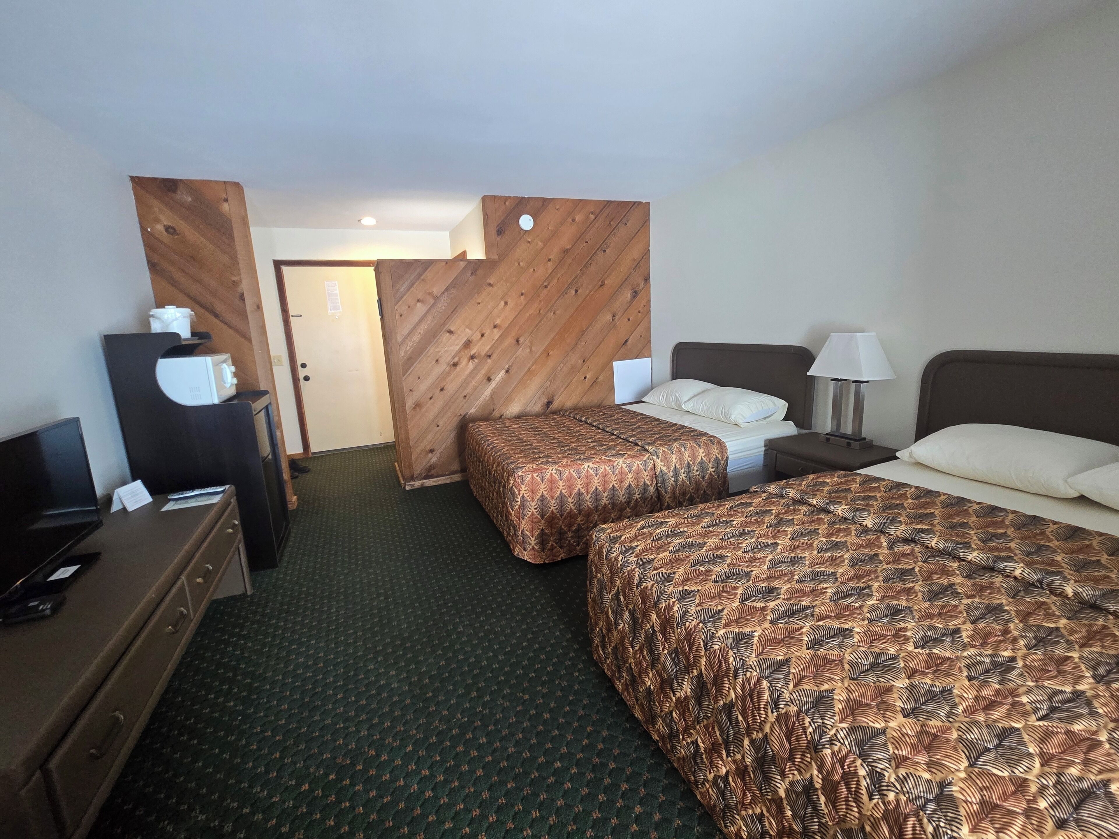 Een hotelkamer met twee bedden, een bureau, een dressoir en een magnetron.