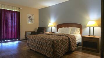 A hotel room with a large bed, two bedside lamps, a chair, a desk, and a window with curtains.