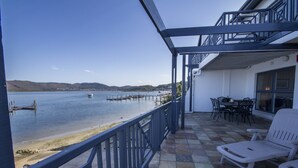 Un balcón con vista a un lago, un muelle y una mesa con sillas.