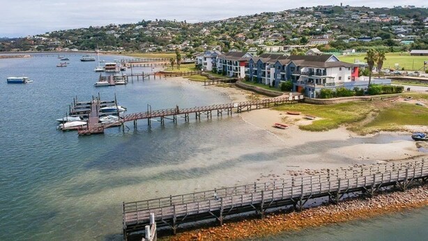 Un hotel costero con un muelle que se adentra en el agua, rodeado de una zona residencial.