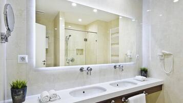 Un baño moderno con un espejo grande, dos lavamanos, una ducha y un perchero para toallas.