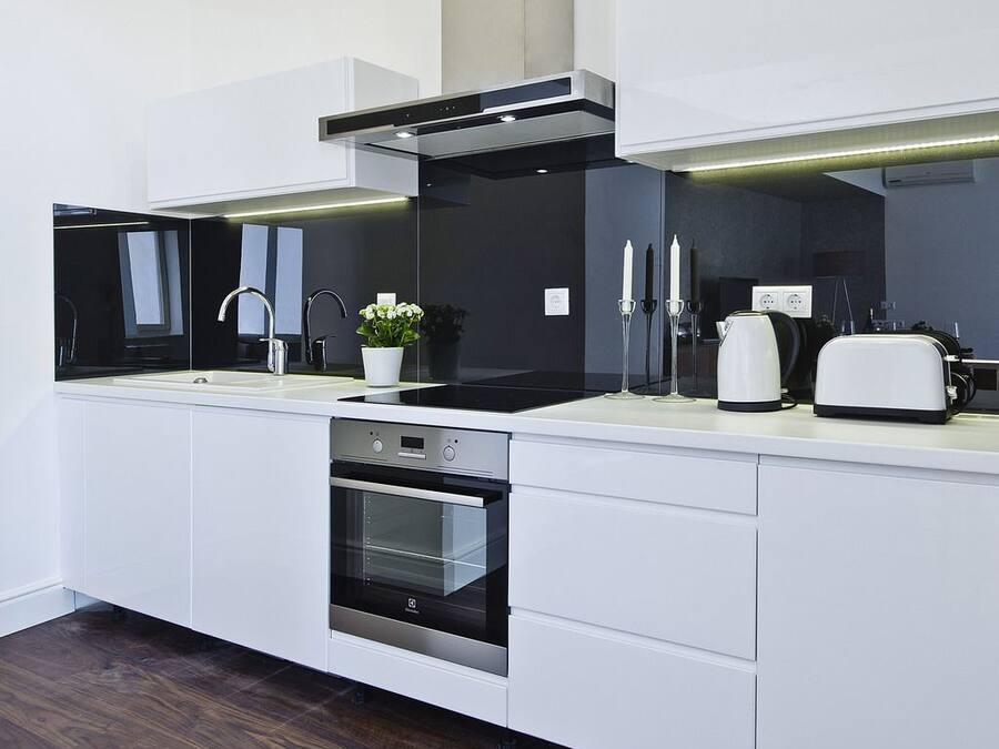 A modern kitchen with white cabinetry, a built-in oven, a black stovetop, and a white countertop.