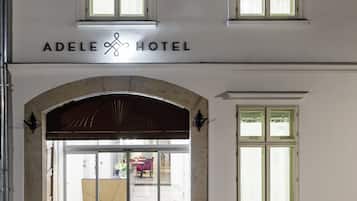 Het uiterlijk van Hotel Adele met een geplaveid voetpad, grote ramen en een klassiek architectuurontwerp.