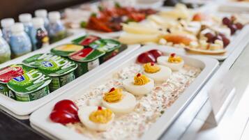 Ein Buffet mit verschiedenen Speisen, darunter Joghurt, Eier mit Kräuterfüllung sowie eine Auswahl an Früchten und Käse.