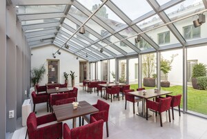 Un comedor interior moderno con techos de vidrio, sillas tapizadas en rojo y mesas.