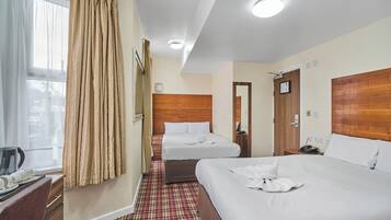 A hotel room with two beds, a wooden headboard, a coffee maker, and a telephone on the nightstand.