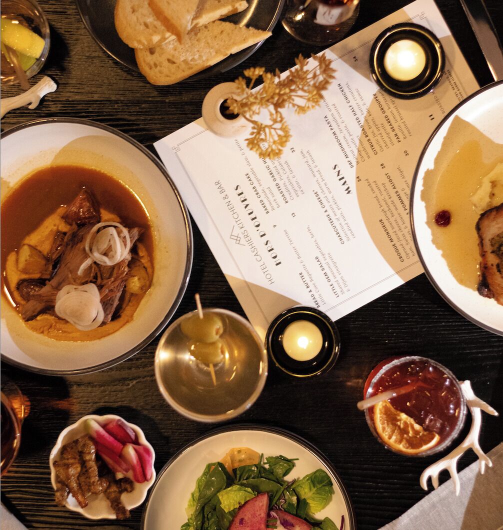 A dining table with various dishes, including soup, salad, and bread, along with a menu and candles.