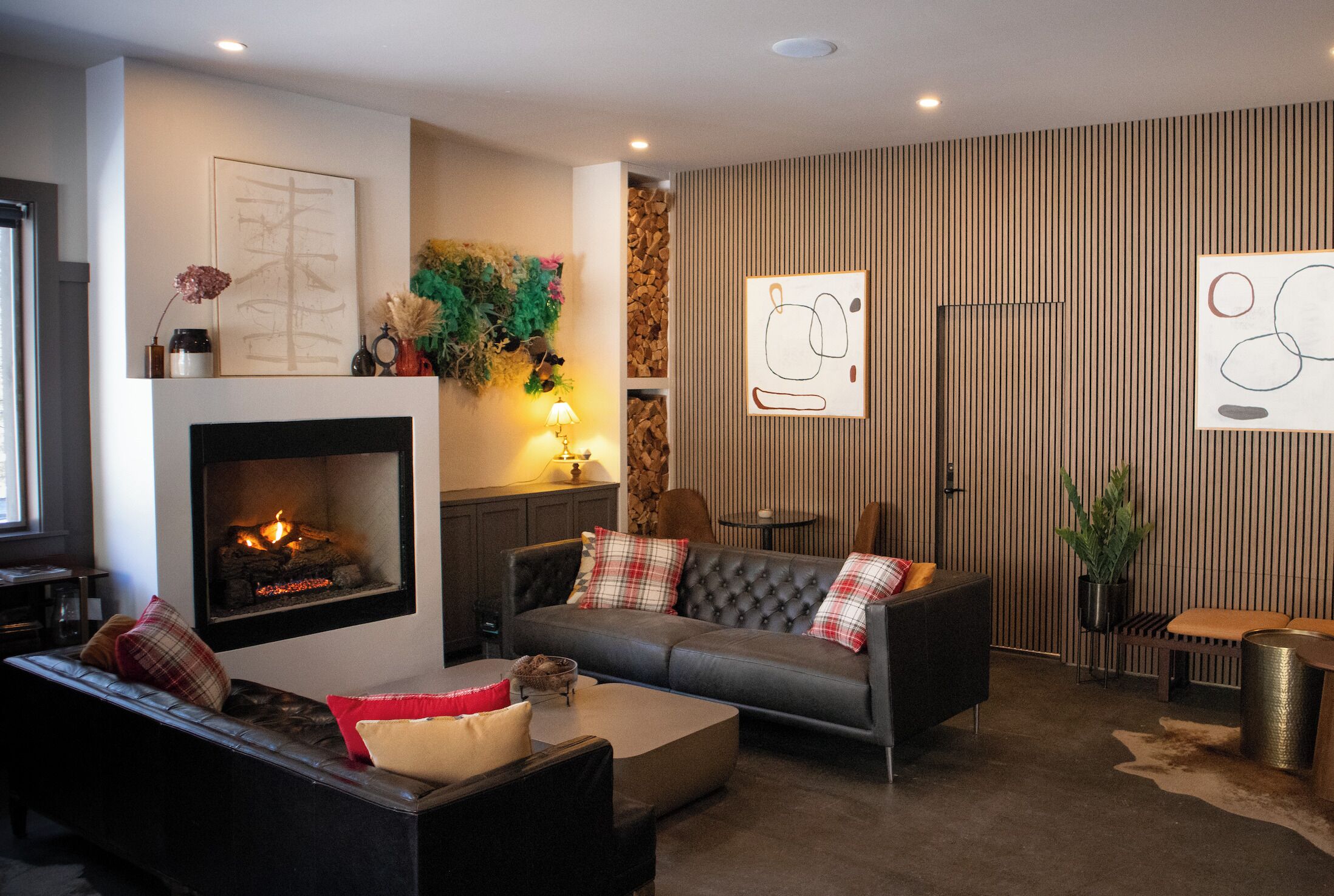 Una sala de estar moderna con chimenea, un conjunto de sofá, una mesa de centro y decoración en la pared.