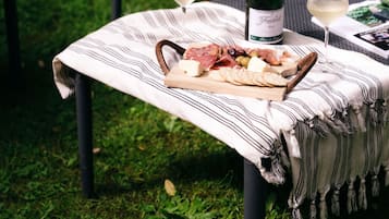 A table set outdoors with a bottle of wine, glasses, and a charcuterie board.