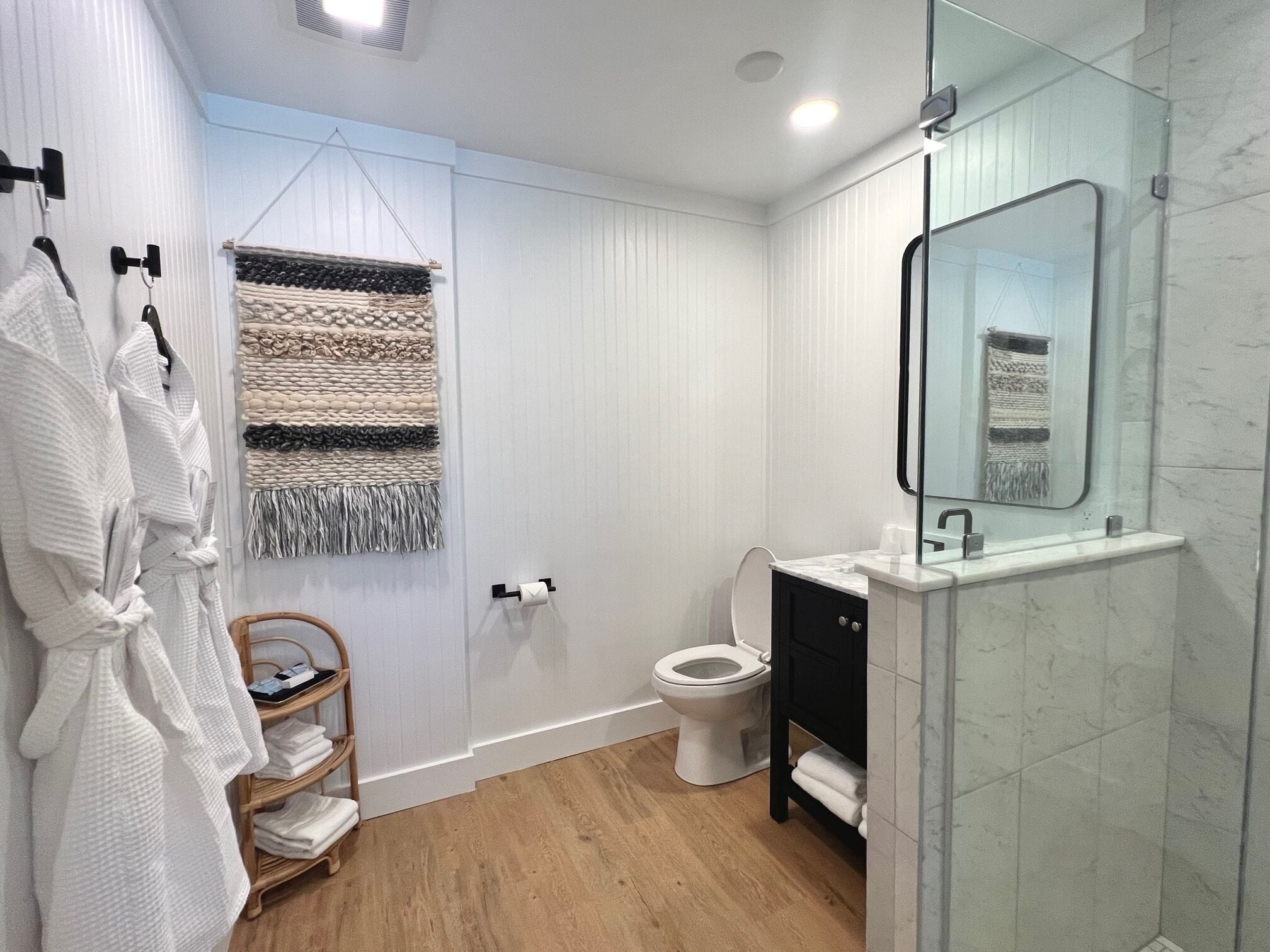 A modern bathroom with a glass shower enclosure, a white toilet, and a black vanity.