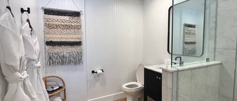 A modern bathroom with a glass shower enclosure, a white toilet, and a black vanity.