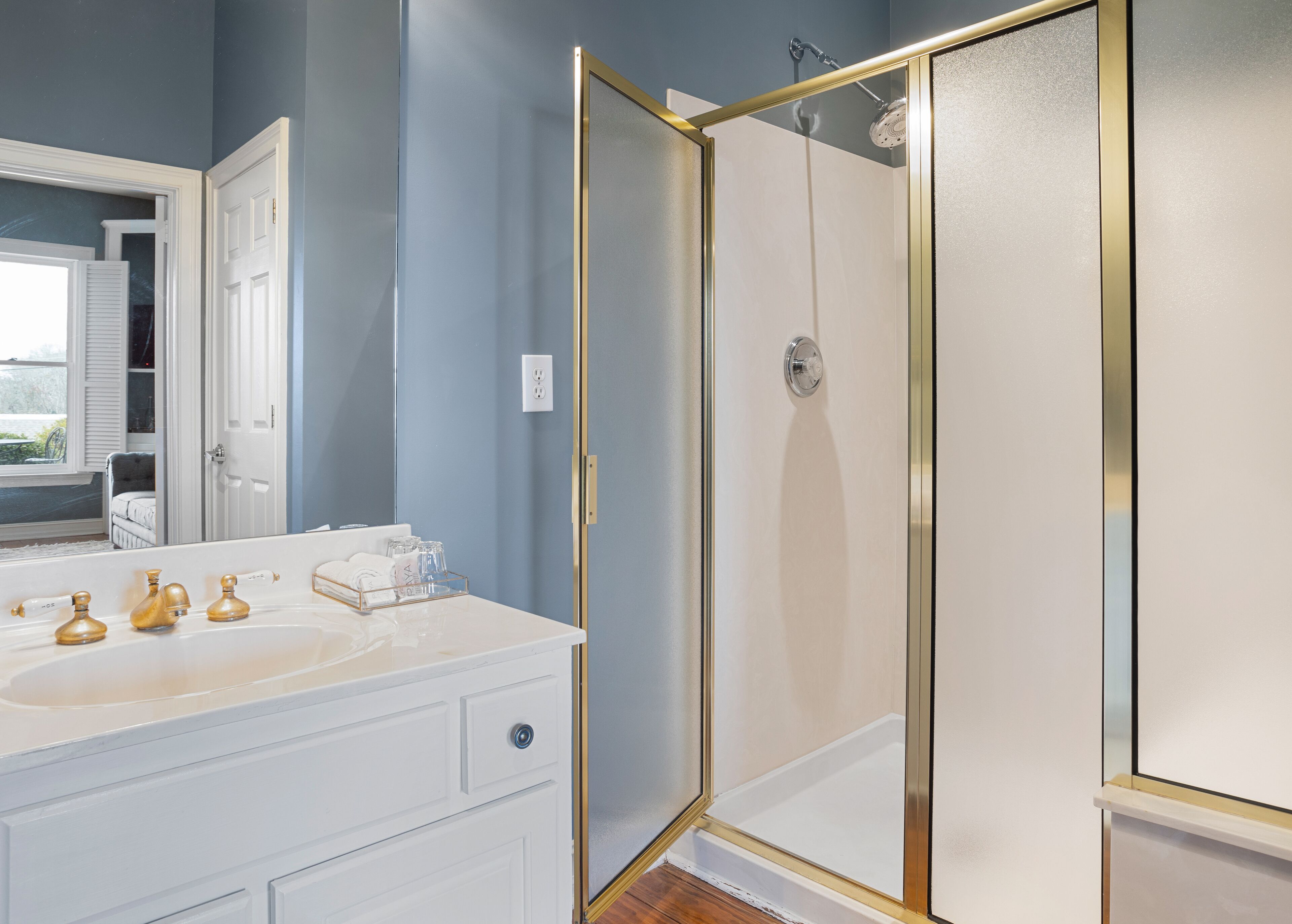 A bathroom with a white vanity, a glass shower enclosure, and a large mirror.