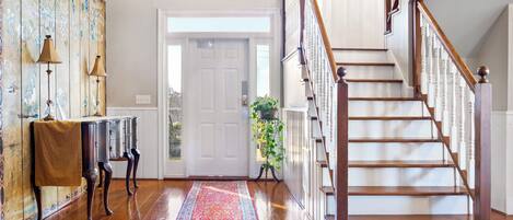 A wooden staircase with white balusters and a handrail, leading to an upper floor.