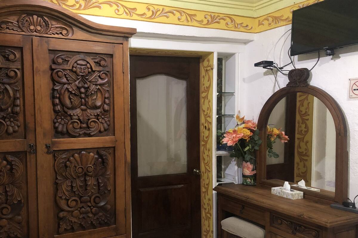 Ein Zimmer mit einem Holzschrank, einem Spiegel und einem Regal mit Blumen.