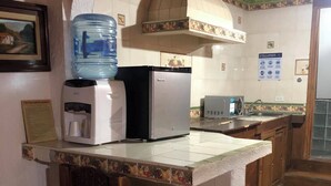 A kitchen with a water dispenser, a refrigerator, a coffee maker, a toaster, and a sink. - Hotel Eden de los Angeles (San Miguel de Allende)