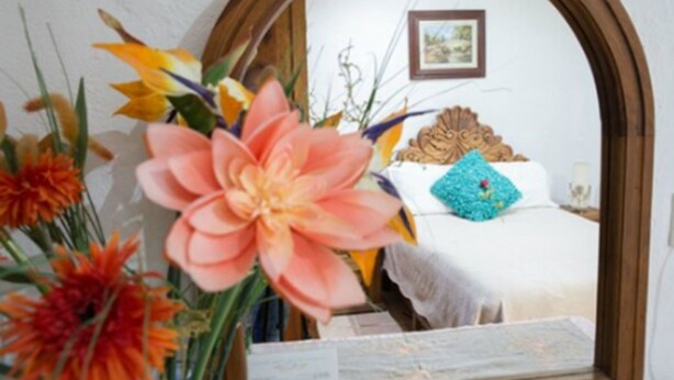 A room with a bed, a mirror, and a floral arrangement. - Hotel Eden de los Angeles (San Miguel de Allende)