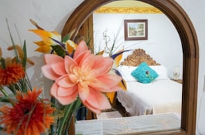 A room with a bed, a mirror, and a floral arrangement. - Hotel Eden de los Angeles (San Miguel de Allende)