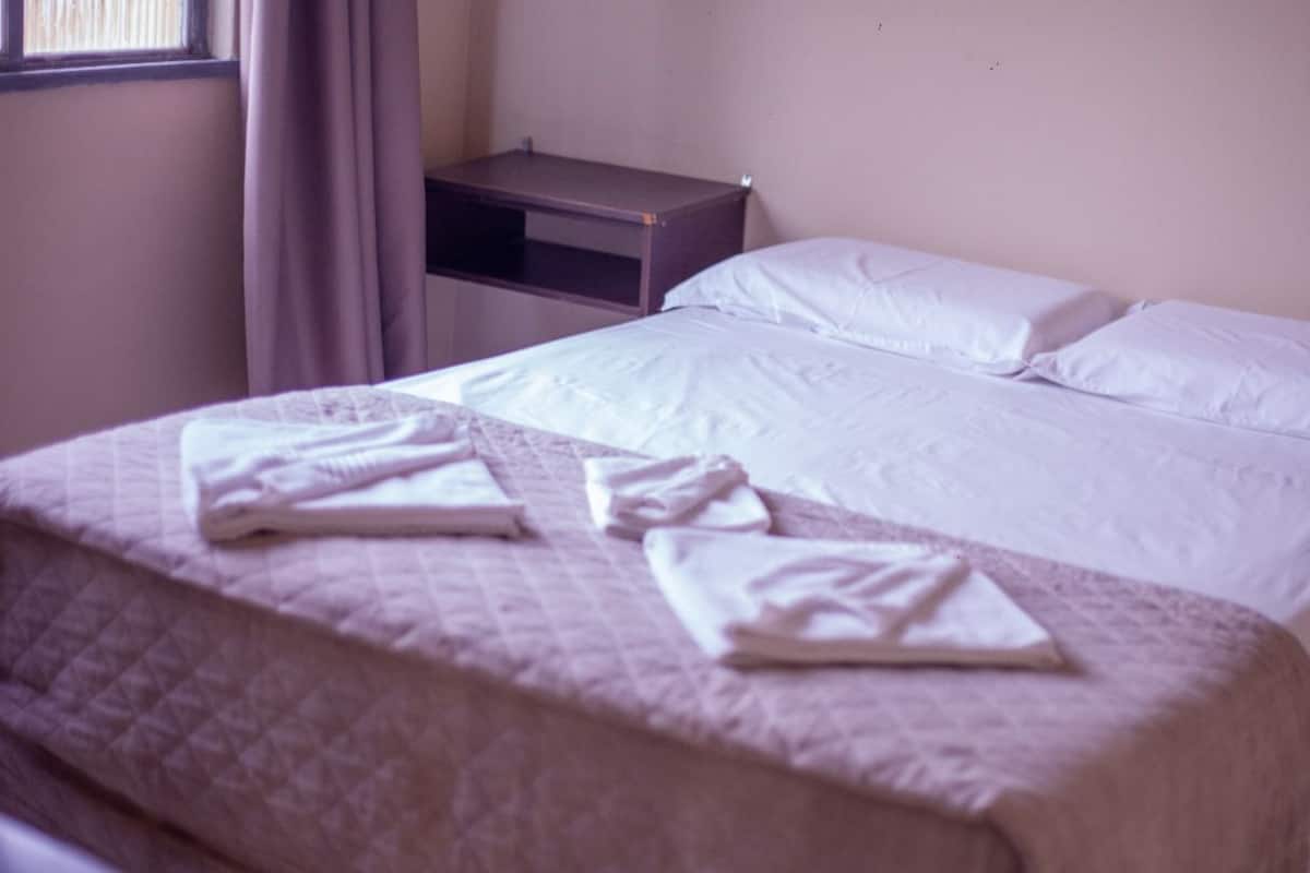 Un lit simple avec une couvre-lit matelassé et deux serviettes pliées posées dessus.