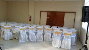 Un salón de conferencias con filas de mesas blancas, cada una con una silla adornada con un lazo amarillo.