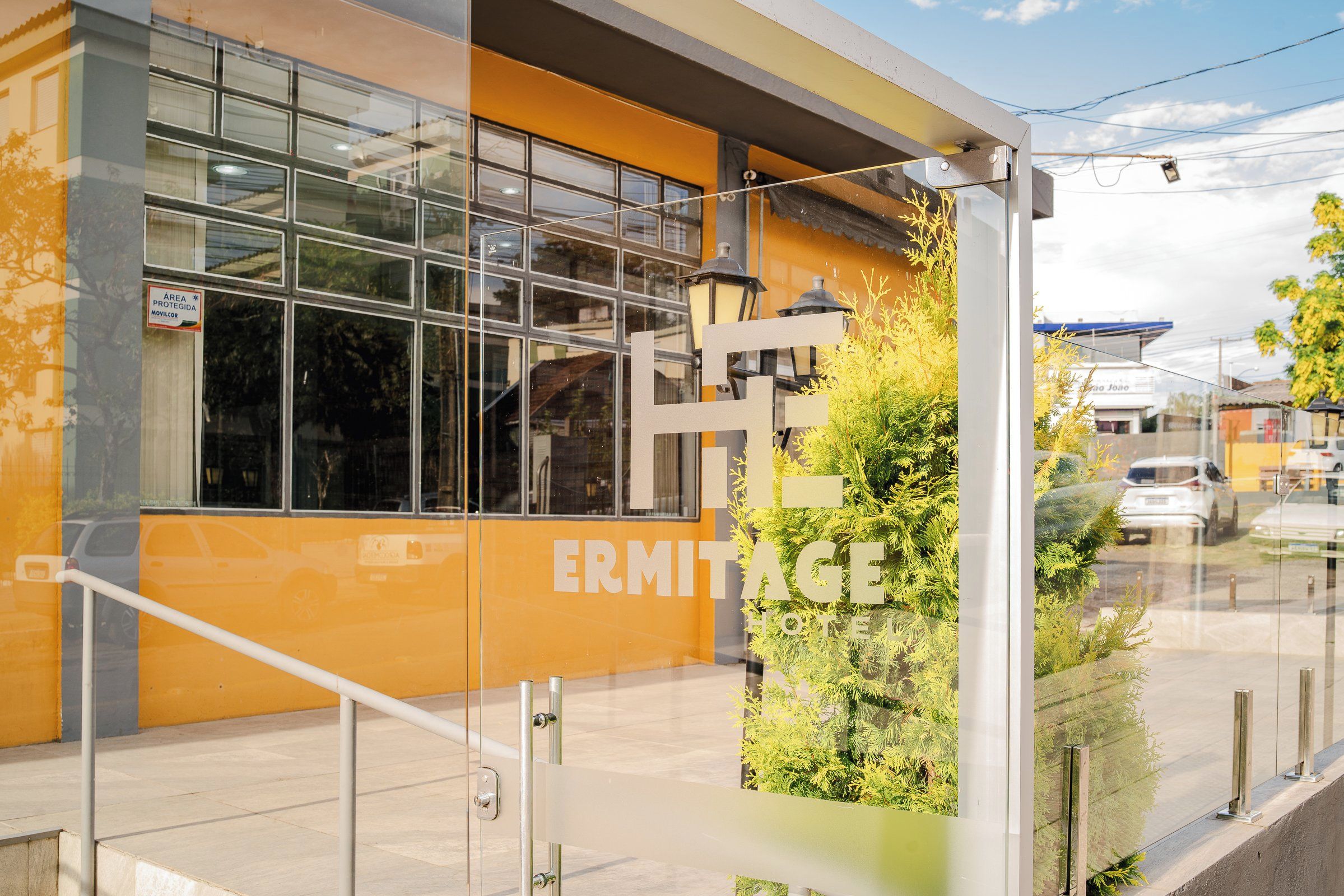 A modern building with large windows and a sign that reads 'ERMITAGE HOTEL'.