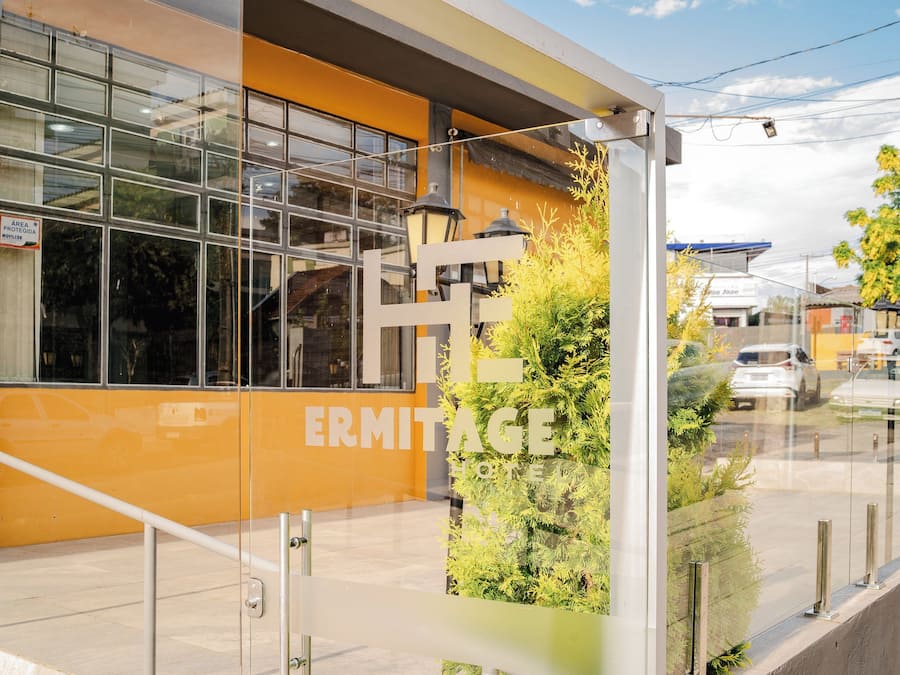 A modern building with large windows and a sign that reads 'ERMITAGE HOTEL'.