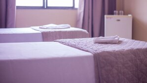 Una habitación de hotel con dos camas, cada una con una toalla doblada con esmero.