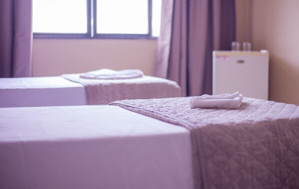 A hotel room with two beds, each with a neatly folded towel.