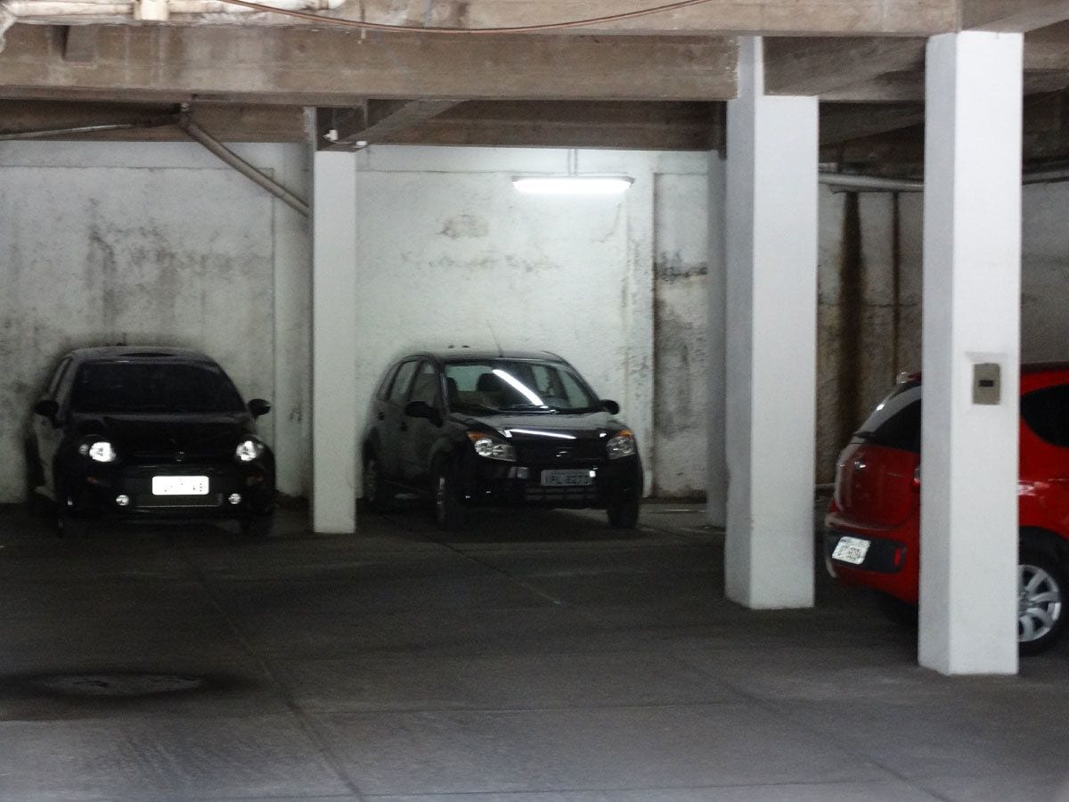 A parking garage with three cars parked in individual spaces.
