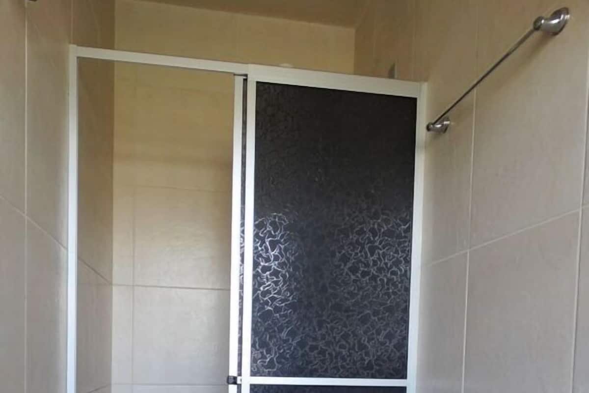 Une douche avec une porte coulissante, des toilettes et un porte-serviettes.