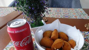 Una mesa con un mantel de mosaicos coloridos, una lata roja de Coca-Cola y un plato de comida frita.