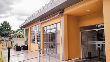 A hotel entrance with a yellow facade, large windows, and a visible entrance door.