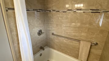 A bathroom with a bathtub, shower, and a towel rack.