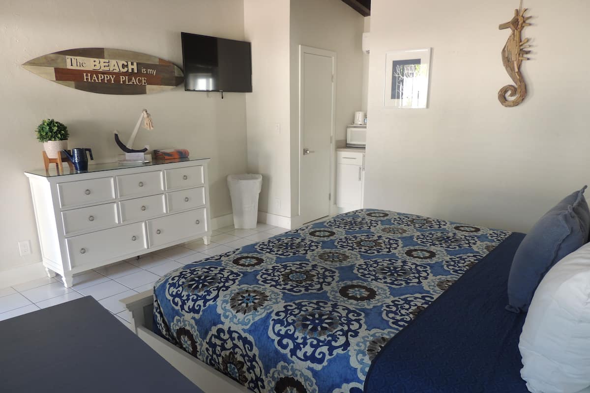 A bedroom with a bed, a dresser, a television, and a seahorse decoration.
