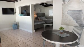 A spacious living area with a round dining table, a sofa, and a TV mounted on the wall. - Sands of Islamorada (Islamorada)