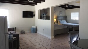 A compact, well-lit room with a bed, bedside table, and a small seating area. - Sands of Islamorada (Islamorada)