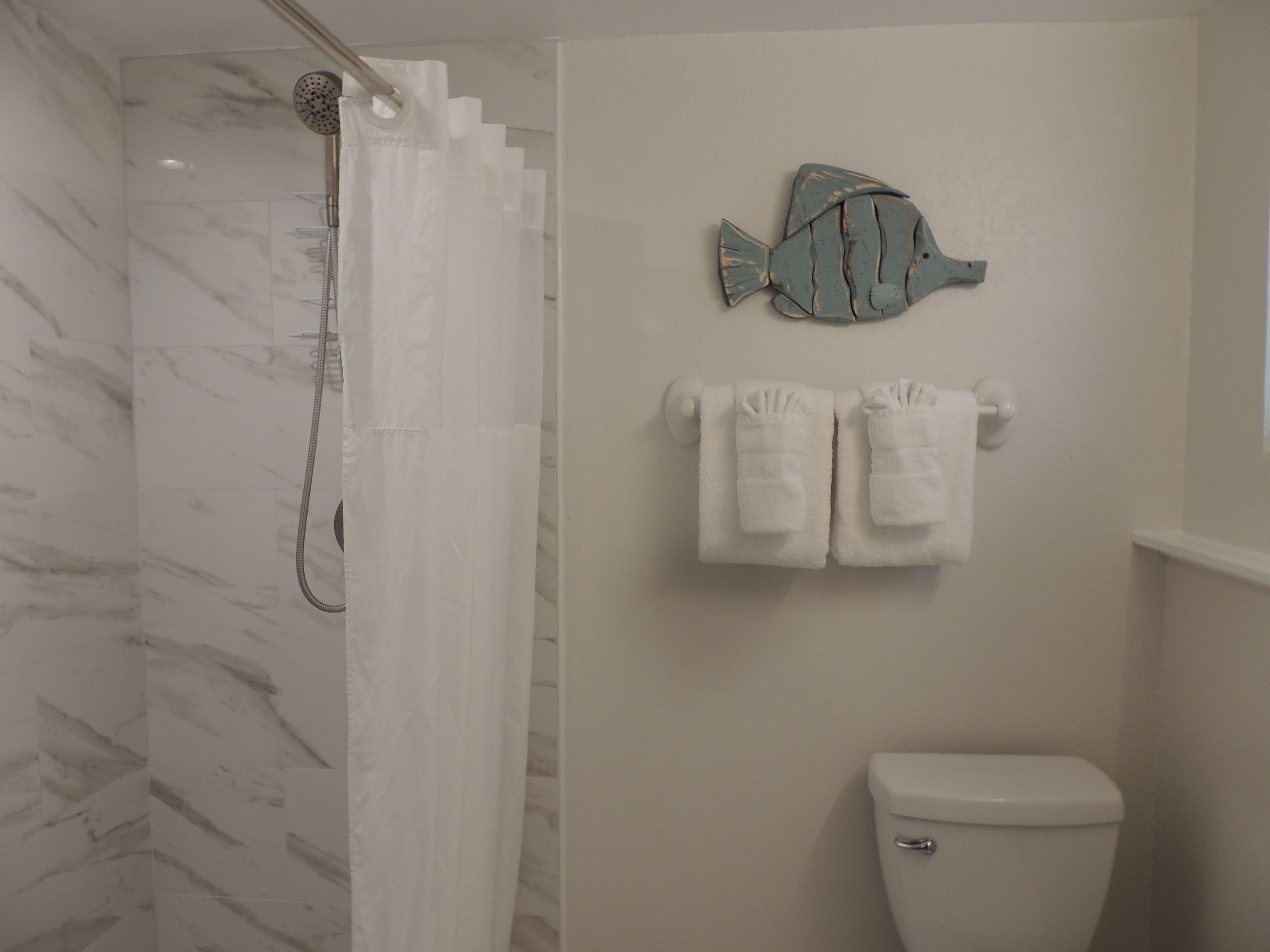 A bathroom with a shower, toilet, and towels.