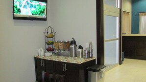 Una cocina compacta con una mesa de comedor, sillas, un televisor y varios electrodomésticos.