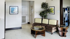 Un vestíbulo de hotel con un sofá, dos mesas redondas, una planta en maceta y cornamentas de ciervo montadas en la pared.