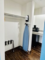 Un baño pequeño con un perchero, una toalla azul colgada, un microondas y un lavabo.