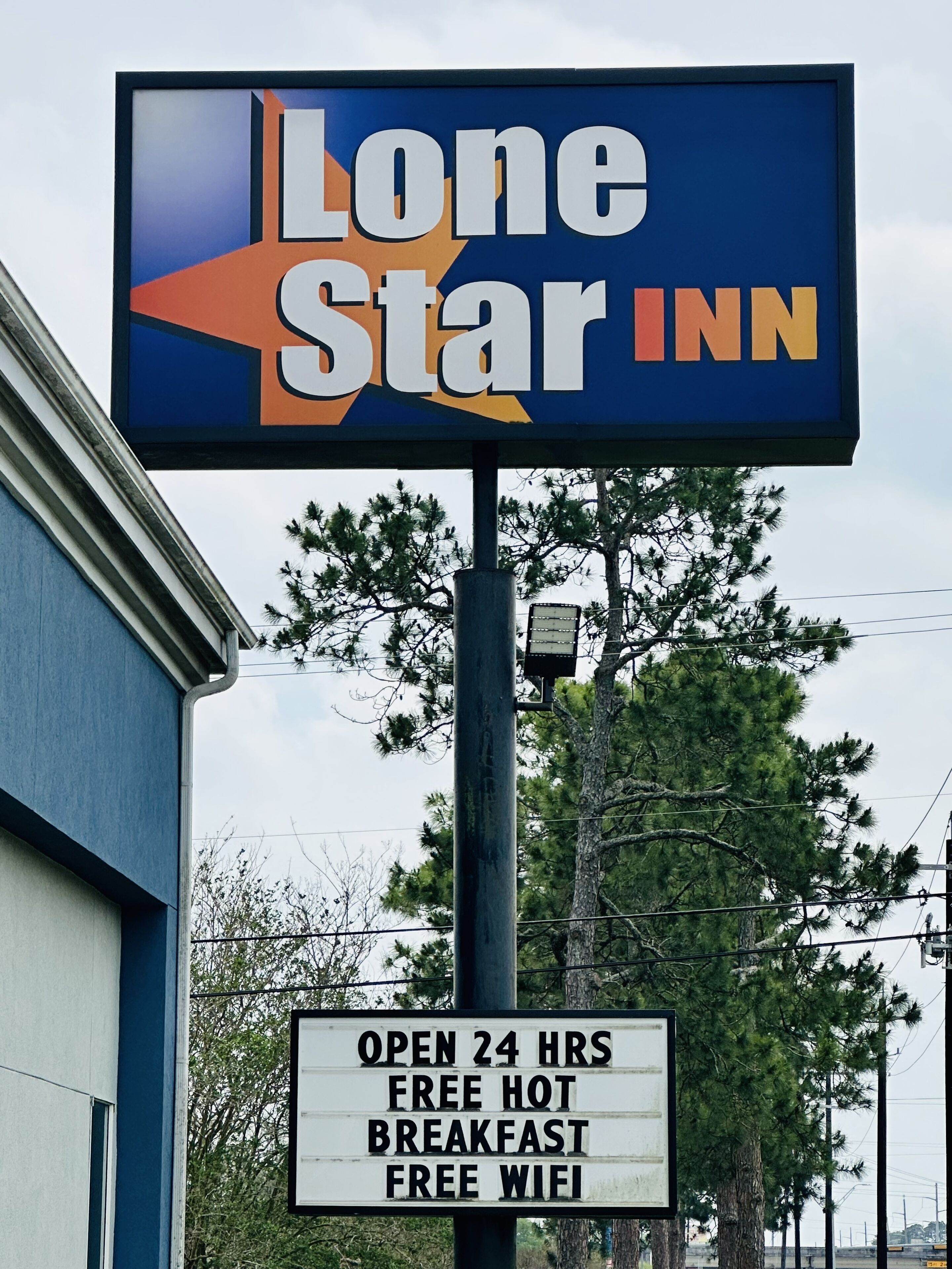 Placa do Lone Star Inn com comodidades como abertura 24 horas, café da manhã quente gratuito e WiFi gratuito.