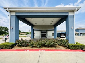 A building with a covered entrance, a fire lane, and a no parking sign.