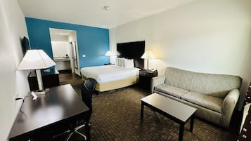 A hotel room with a bed, a sofa, a desk, and a TV.