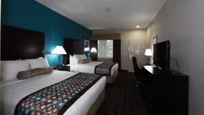 Habitación de hotel con dos camas, televisión y escritorio.