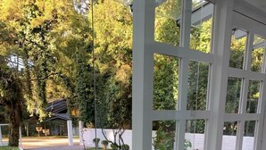 Un espacio al aire libre techado con suelo de baldosas, un sendero y vistas a un edificio y árboles.