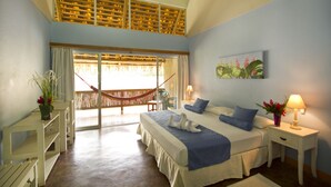 A bedroom with a bed, nightstands, a desk, a hammock, and a window with curtains.
