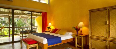 A room with a bed, a wooden bench, a nightstand, and a large window.