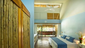 A bedroom with a bed, bedside table, lamp, and a view of a hammock outside.