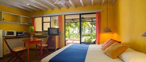 Habitación de hotel con cama, escritorio, televisor y ventana con cortinas.