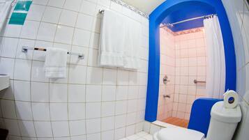Une salle de bain avec des murs recouverts de carreaux blancs, une cabine de douche bleue et des toilettes blanches.